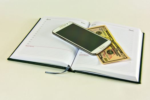 Diary, smartyon and banknote on a white background

