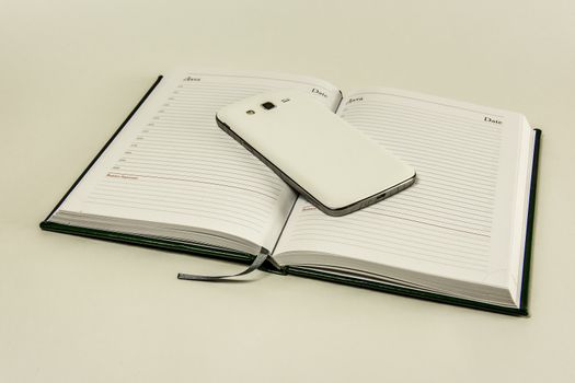 Open diary and smartphone on a white background

