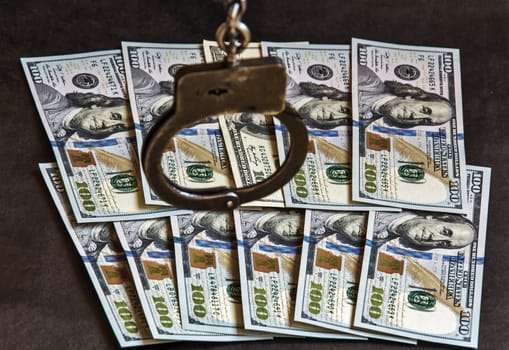 Silhouette of handcuffs on the US currency bills