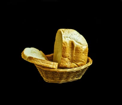 Loaf of white bread in a straw basket on a black background



