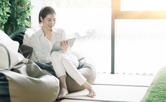 Asian woman usgin smart tablet at home.