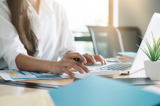 Close up of business woman or accountant working on calculator to calculate business data, accountancy document and laptop computer at office, business concept.