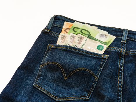 In the back pocket of blue jeans pants are banknotes in denominations hundred and fifty euro notes and three thousand Russian rubles