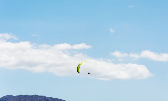 Against the background of mountains and blue sky with clouds athletes are planning a paraglider