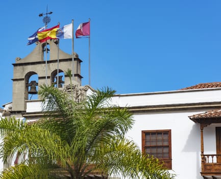 On the roof of the house with the bells attached flagpoles with flags