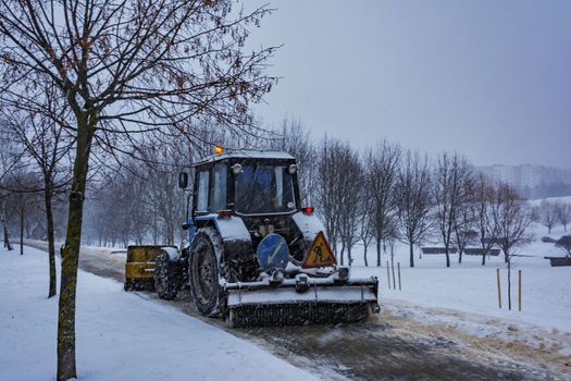 Traktor Balorus rensar snö från trottoaren under snöfall