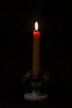 Lit candle on black background