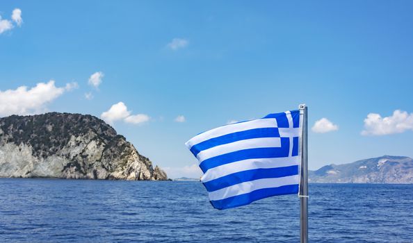 Against the backdrop of the sea and the mountains of Greece flag flies