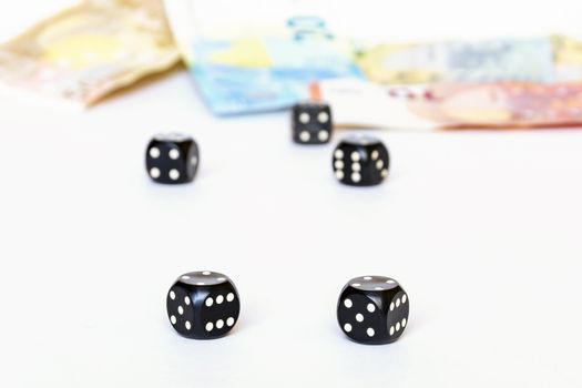 On a white background are clearly visible two dice for the game of poker. Three cubes and banknotes can be seen in the background.
