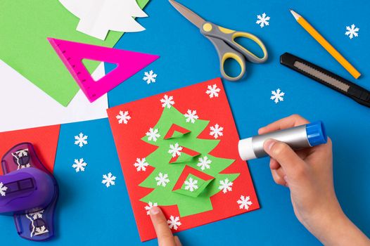 Child makes card with Christmas tree. Original children's art project. DIY concept. Step-by-step photo instructions. Step 9. Decorate card with snowflakes