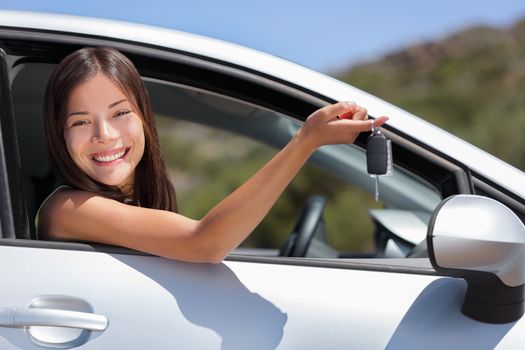 New car driver woman holding keys for travel road trip. Happy young Asian girl with rental lease or purchase of automobile at dealership.