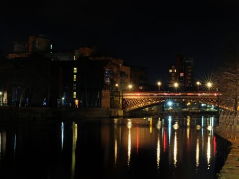 crown point bridge crossing the river aire in leeds at night with lights and surrounding buildings reflected in the water