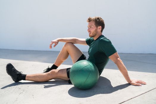 Fit athlete man relaxing at fitness gym during medicine ball workout. Healthy and active lifestyle young adult portrait.