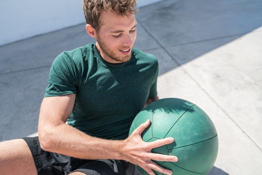Medicine ball exercise russian twist man. Abs workout - fitness athlete working out doing exercises training oblique muscles on outdoor floor.