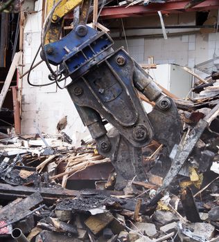 a close up of a heavy demolition claw picking up rubble and debris on a construction site