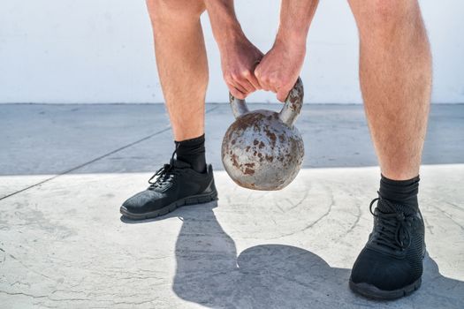 Fitness man cross training lifting kettlebell weight. Closeup of hands holding heavy weights for deadlift or squat workout exercise. Weightlifting concept.