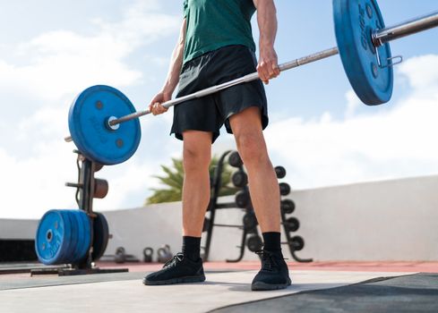 Weightlifting fitness man bodybuilding or powerlifting at outdoor gym. Bodybuilder strength training lifting barbell weights doing deadlift exercise.