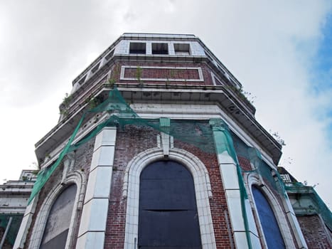 a close up of the abandoned derelict historic former odeon cinema in bradford west yorkshire england with decaying walls overgrown with plants and cracked stonework