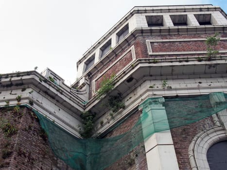 a close up of the abandoned derelict historic former odeon cinema in bradford west yorkshire england with decaying walls overgrown with plants and cracked stonework