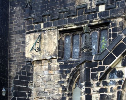 a full frame close up of ancient stonework stained glass windows and a sundial on the medieval church of st john the baptist in halifax now a minster