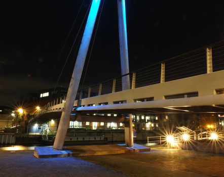 detail of the pedestrian footbridge crossing the river aire in leeds at night with bright lights and illuminated waterside buildings