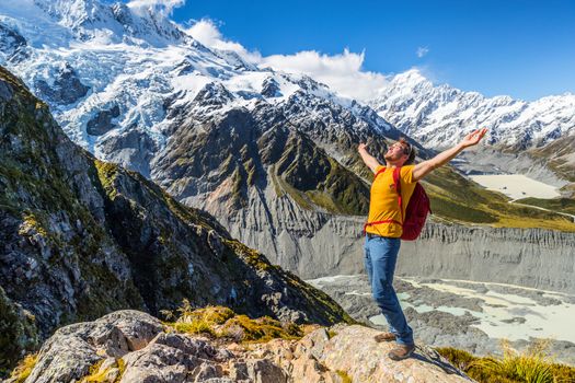 New Zealand success hiker man hiking at Mount Cook. Cheering adventure tourist reaching goal challenge on top of mountain summit trail.