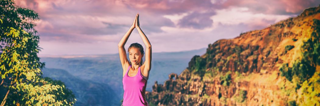 Yoga retreat in Kauai nature panoramic banner. Asian girl practicing meditation outdoors in sunset sitting with praying hands overhead for tree pose.