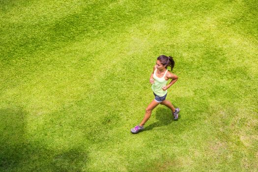 Active sport woman runner running on grass outdoors training for marathon. Asian chinese sporty girl on morning run.