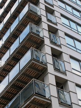 corner view of a modern urban apartment building with black cladding and glass balconies reflecting other buildings