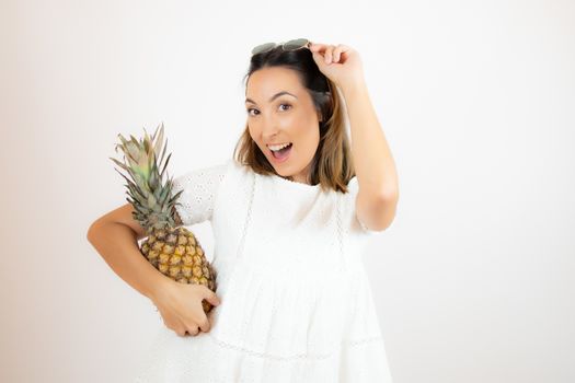 Beautiful young woman picking up a pineapple