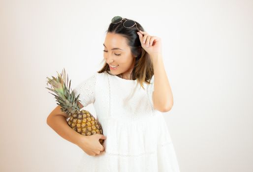 Beautiful young woman picking up a pineapple
