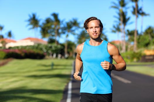 Running athlete man runner training cardio on road for marathon run. Athletic fit young sport fitness model outside in tropical summer city.