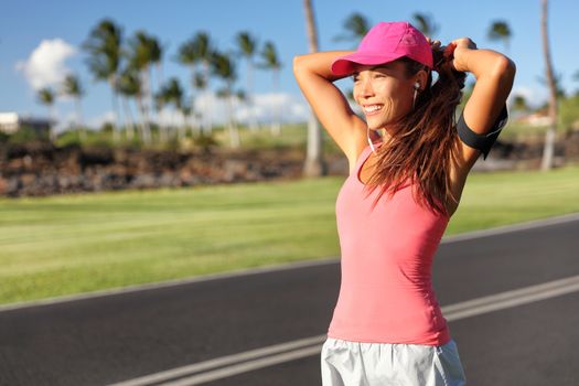 Active Asian runner woman tying hair into ponytail getting ready to run her morning jogging workout. Happy healthy lifestyle. Fitness wellness life.