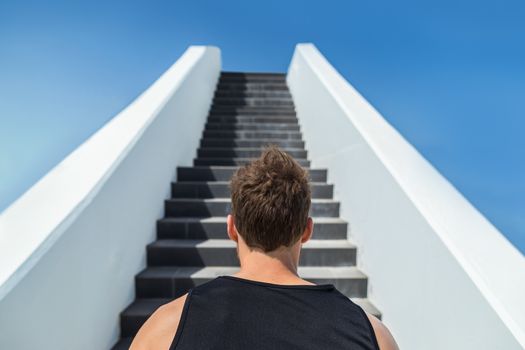 Fitness man looking ahead at stairs climbing challenge. Runner going up running staircase for cardio goal doing weight loss choice in healthy lifestyle. Man choosing difficult path.