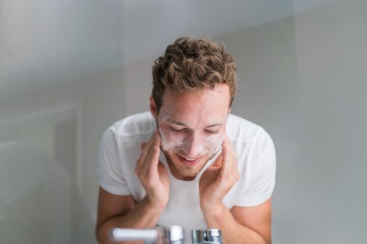 Man washing face with facial cleanser face wash soap in bathroom sink at home.