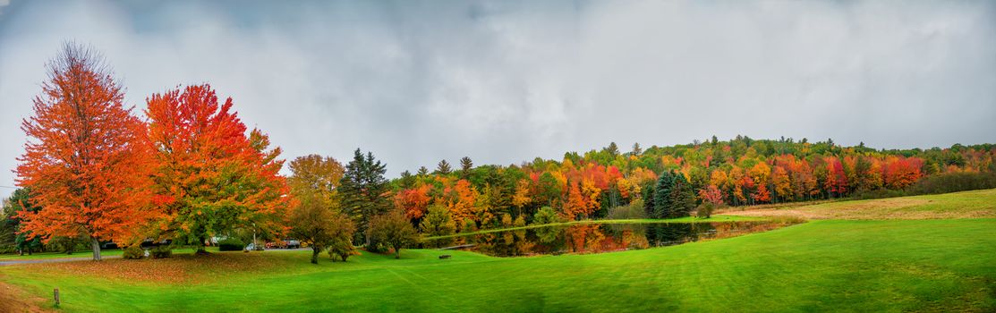 Panoramic view of beautiful Maine foliage landscape with trees and lake reflections.