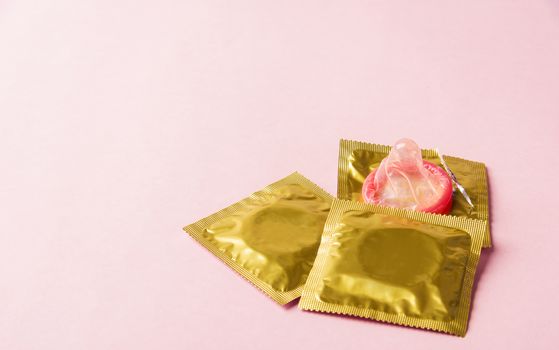 World sexual health or Aids day, Top view flat lay condom in wrapper pack is tear open, studio shot isolated on a pink background, Safe sex and reproductive health concept
