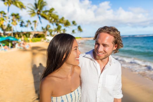 Hawaii travel beach couple laughing together happy on honeymoon vacation. People enjoying hawaiian sunset holidays.