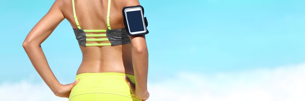 Fitness athlete woman closeup wearing armband for smartphone music listening device. Runner on beach banner crop with copyspace on blue background.