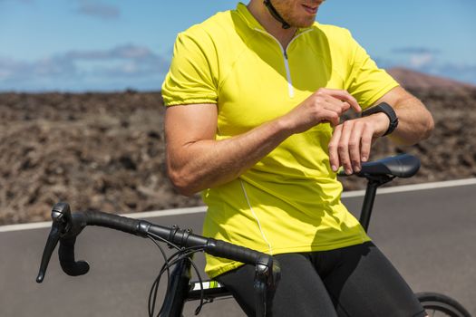 Athlete cyclist using an activity tracker gps smartwatch during biking workout training. Road bike sports man using his watch app for fitness tracking. Healthy lifestyle.