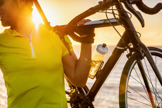 Cyclist carrying road bike at sunset after long day of biking activity riding outdoors. Healthy man living an active lifestyle cycling doing outdoor sports.