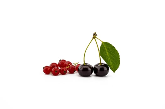 Two ripe cherries with a green leaf and a bunch of red currants isolated on a white background