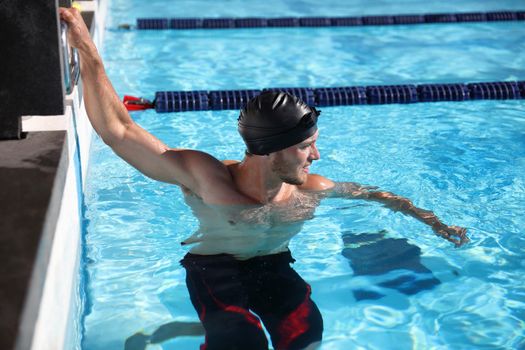 Swimmer sport athlete man at start of competition race in swimming pool - ready to swim. Motivation and concentration in training.