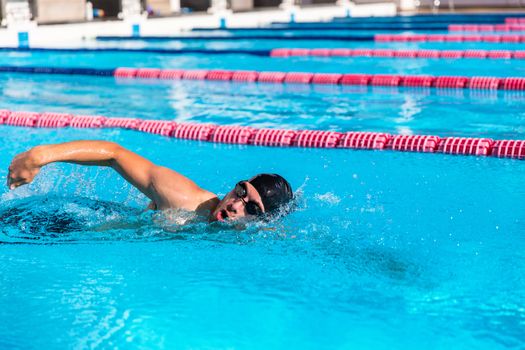 Swimmer man sport training at swimming pool. Professional male athlete doing crawl freestyle stroke technique.
