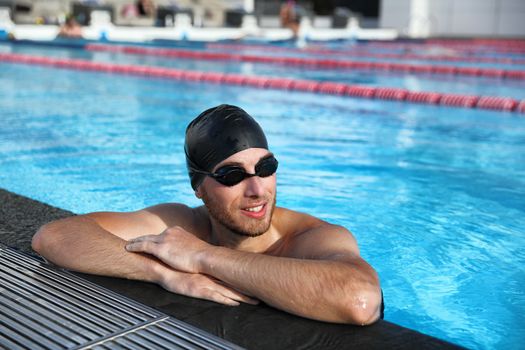 Professional sport swimmer athlete portrait at swimming pool. Active lifestyle healthy fit man wearing cap and goggles.