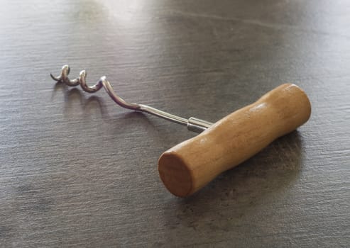 close up simple wooden corkscrew on a grey textured background