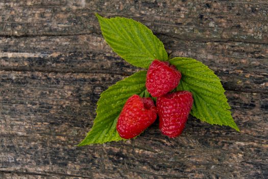 Ripe aromatic raspberries on a wooden background.