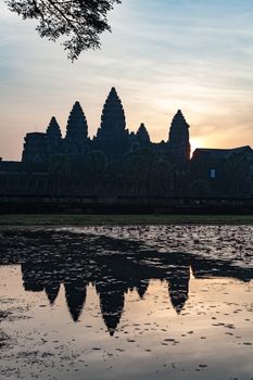 The temple complex of Angkor Watt, Cambodia, with the famous temples of Angkor, Ta Prohm and Bayon. Sunrise picture with the famous towers reflecting in the lake in front 
