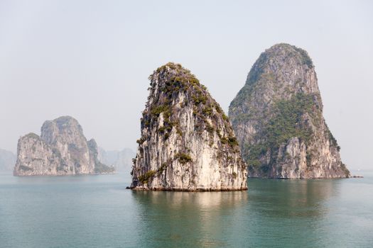 Ha Long Bay, Vietnam, is a World Heritage Site and very popular with tourists. Thousands of towering limestone islands topped by rainforests rising up out of the emerald seas. Cruise ships take tourists for day trips and overnight stays in the bay. , . High quality photo