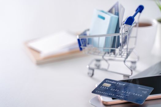 Office online paying, stay home shopping, electronic payment with credit card concept, laptop on white table background with shop cart, close up.